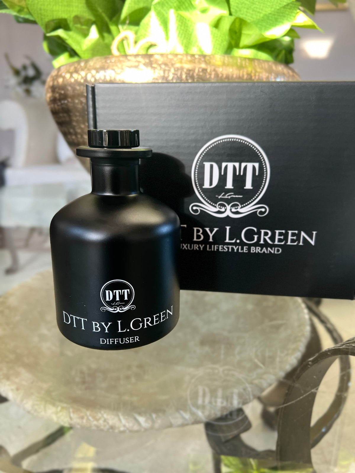 Black diffuser bottle with 'DTT by L. Green' branding on a reflective surface.